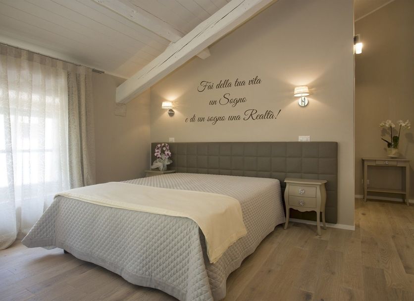 Villa Anna, Lucca bedroom with queen bed, sheer curtains, wall sconces and sloped ceiling