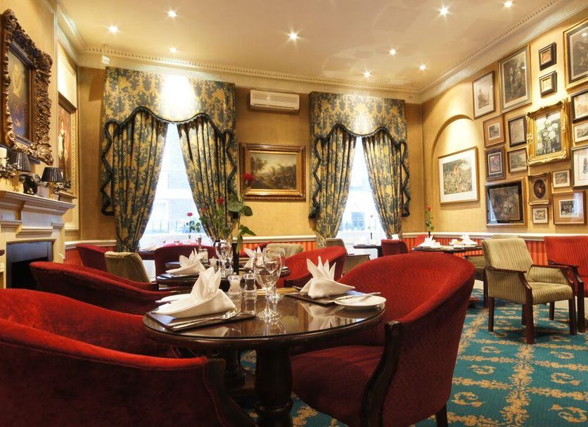 The Leonard Hotel in London lounge with red chairs, framed art walls, and set dining tables