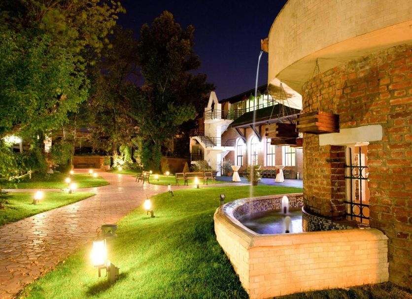Caro Horoscop Hotel in Bucharest with illuminated garden pathway and courtyard fountain at night