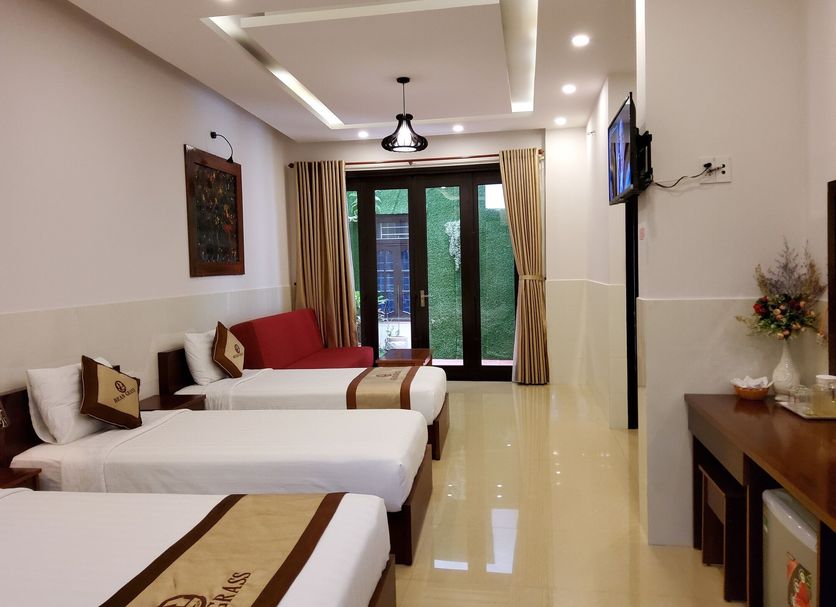 Bean Grass Homestay in Hoi An: guest room with three twin beds and glass doors to a balcony