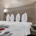 Red Roof Inn Greenville guest room with neatly made bed, white pillows and bedside wall lamps