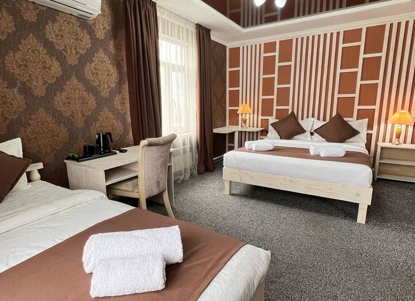 Kausar Hotel in Bishkek room with two beds, desk, patterned wallpaper and wall-mounted air conditioner