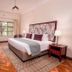 Bronte Hotel Harare guest room with king bed, patterned headboard, window, and wall-mounted TV