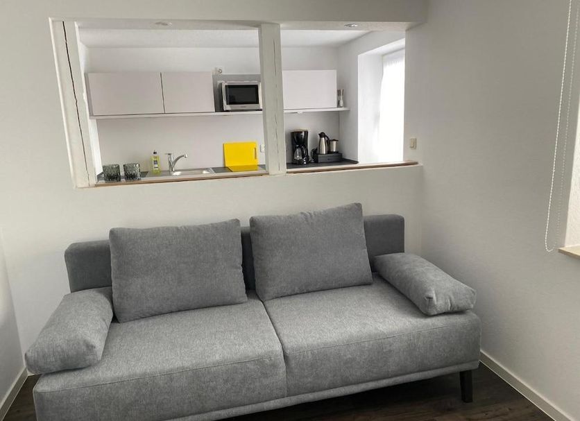 Weserlounge Hotel Garni in Hessisch Oldendorf, gray sofa seating area with kitchenette pass-through