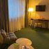 Hotel Westfalia Halle guest room with chair, desk, lamp, wall-mounted TV and large window
