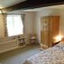 Manor Farm B&B in Marlborough bedroom with floral bedspread, wooden wardrobe, chair and window