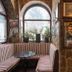 Turn Hostel in Ljubljana: stone-walled lounge with striped benches, arched windows, and small tables