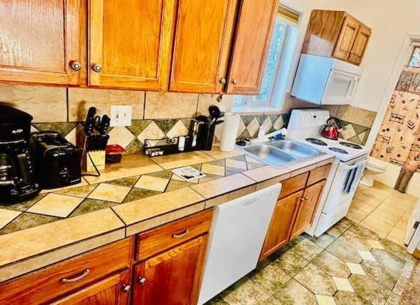 Lower Unit-Yosemite Woods-Inside Yosemite kitchen in Yosemite West with wood cabinets, tiled counters, and white appliances