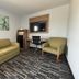 Jacksonville Inn & Suites, Jacksonville guest room with sofa, armchair, desk, and wall-mounted TV