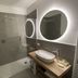 Hotel Al Sole Bardolino bathroom with walk-in shower, oval mirror, and wood vanity in Bardolino