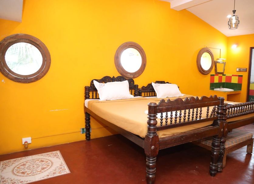 La Villa Creole in Pondicherry guest room with carved wooden bed and bright yellow walls