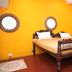 La Villa Creole in Pondicherry guest room with carved wooden bed and bright yellow walls