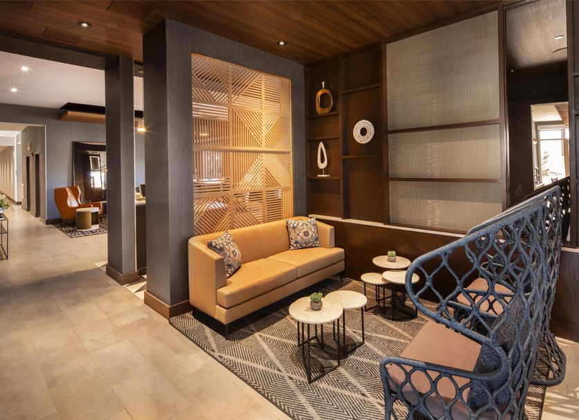 Hyatt Place South Reno lounge with tan sofa, patterned chairs and decorative railing in Reno