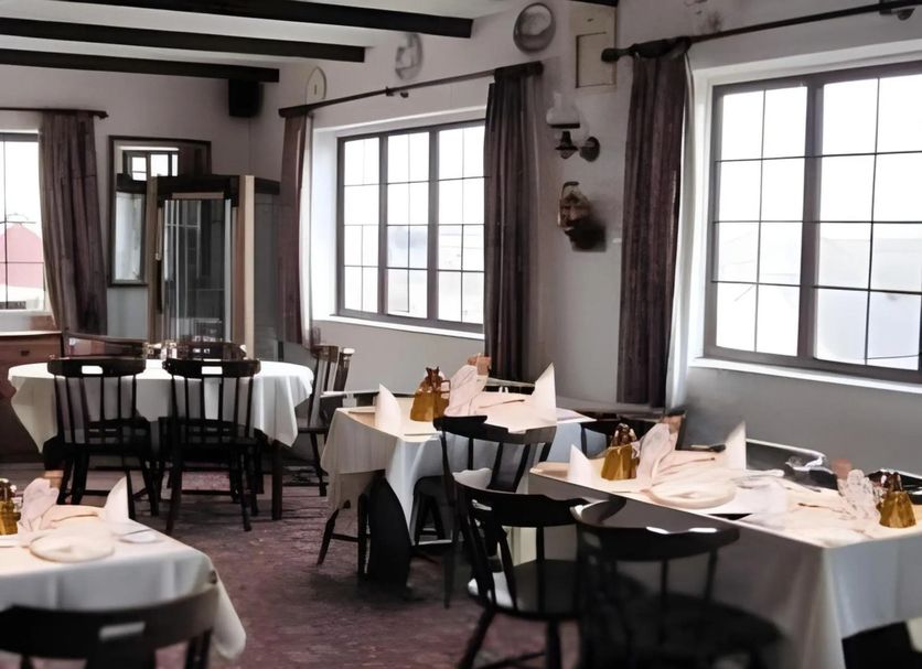 Green Acre Motel in Bridgend dining room with set tables, chairs, and large windows overlooking water.