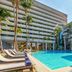 Melia Habana in Havana with palm-lined outdoor pool and sun loungers between high-rise hotel buildings