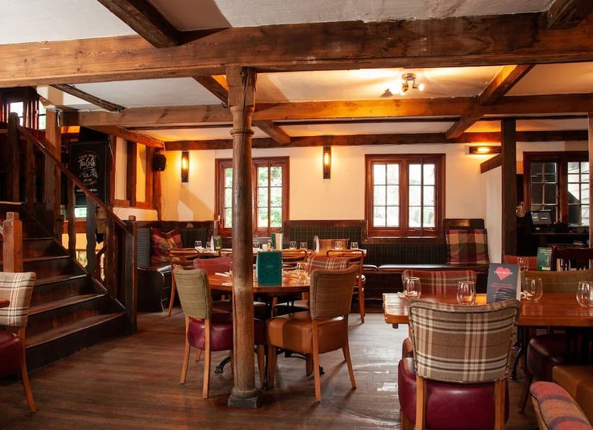 The Wiremill in Lingfield: rustic restaurant dining room with wooden beams, tables, and staircase