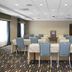Hampton Inn Pittsburgh-Bridgeville meeting room in Bridgeville with tables, blue chairs, and projection screen