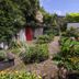 Haka Lodge Christchurch garden courtyard with brick path, lush plants, and red door