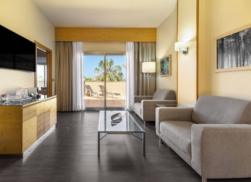 Elba Costa Ballena Beach & Thalasso Resort room with sofa, TV, and balcony view in Cadiz