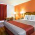 Motel 6 Clarksville TN guest room with king bed, orange accent wall, desk and bedside lamps