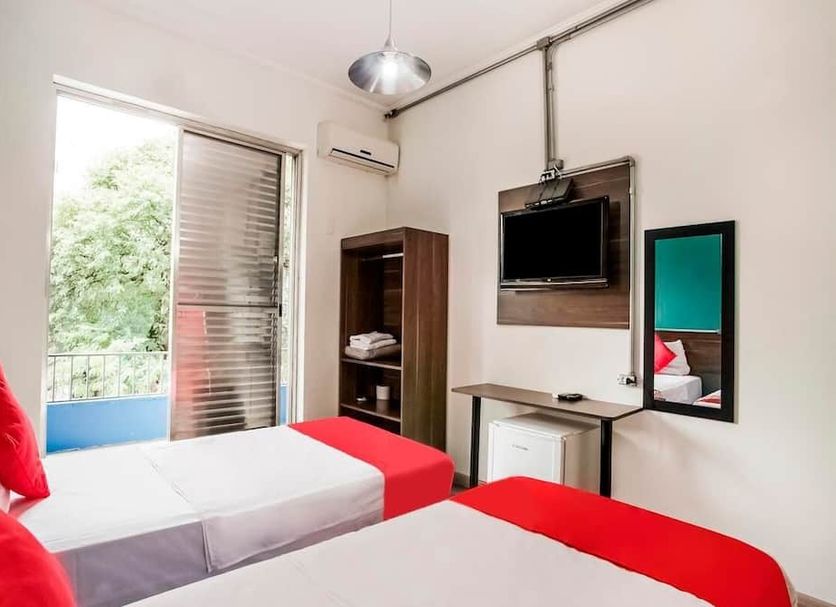 Hotel Consulado Avenida Paulista room in Sao Paulo with twin beds, wall-mounted TV and balcony door