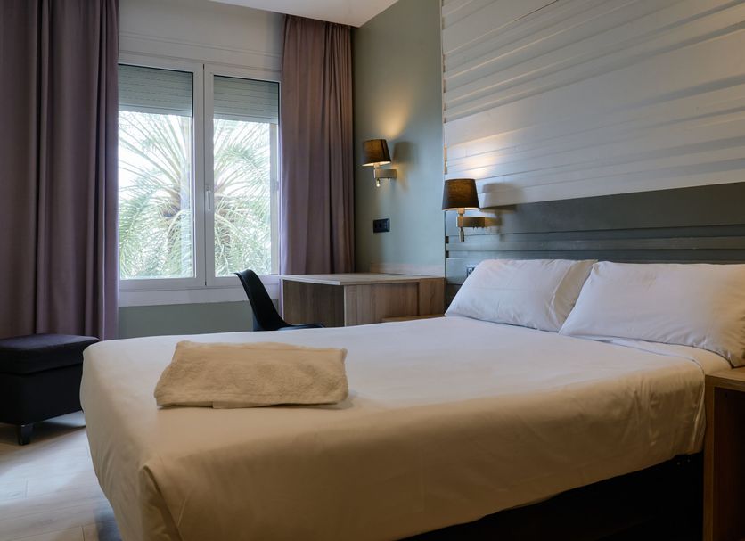 Hotel Miramar Badalona guest room with double bed, window view, and wall sconces in Badalona