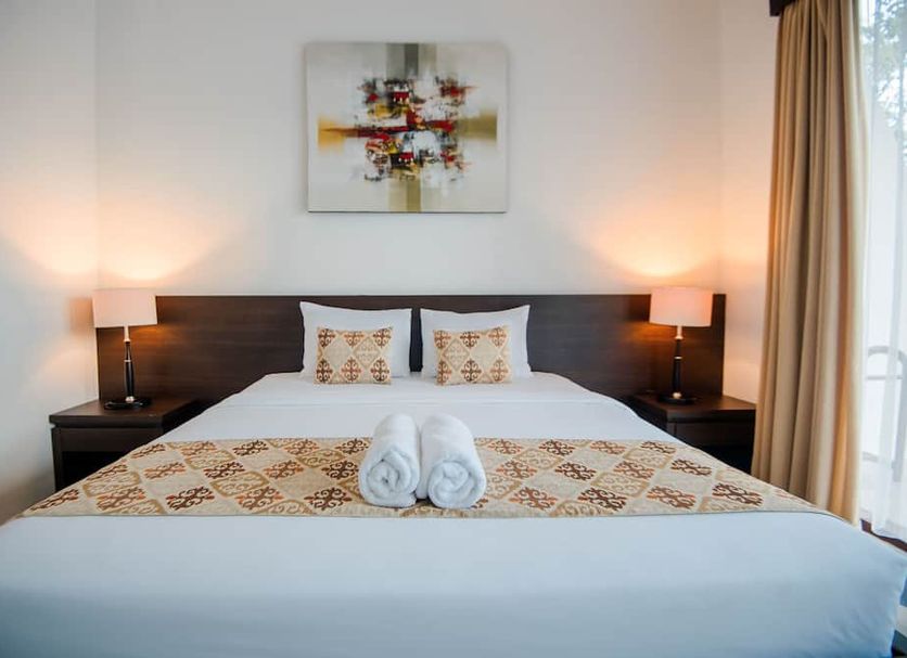 D' Kubu Pratama Homestay in South Kuta bedroom with neatly made bed, bedside lamps and sheer curtains