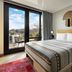 Moxy Asheville Downtown guest room with balcony, bed, green chair, and city-view doors in Asheville