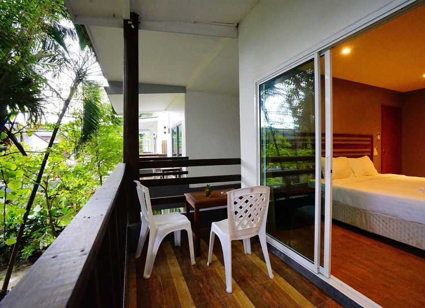 Apple Beachfront Resort, Ko Chang: balcony with chairs and table beside a bedroom and tropical greenery