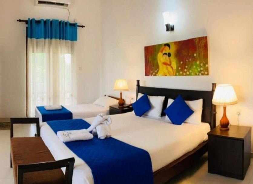 Blue Spring Hotel Wadduwa room with two beds, blue accents, and wall art in Wadduwa.