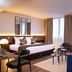Hotel Du Port in Nogent-sur-Marne guest room with king bed, sofa, chairs and large windows