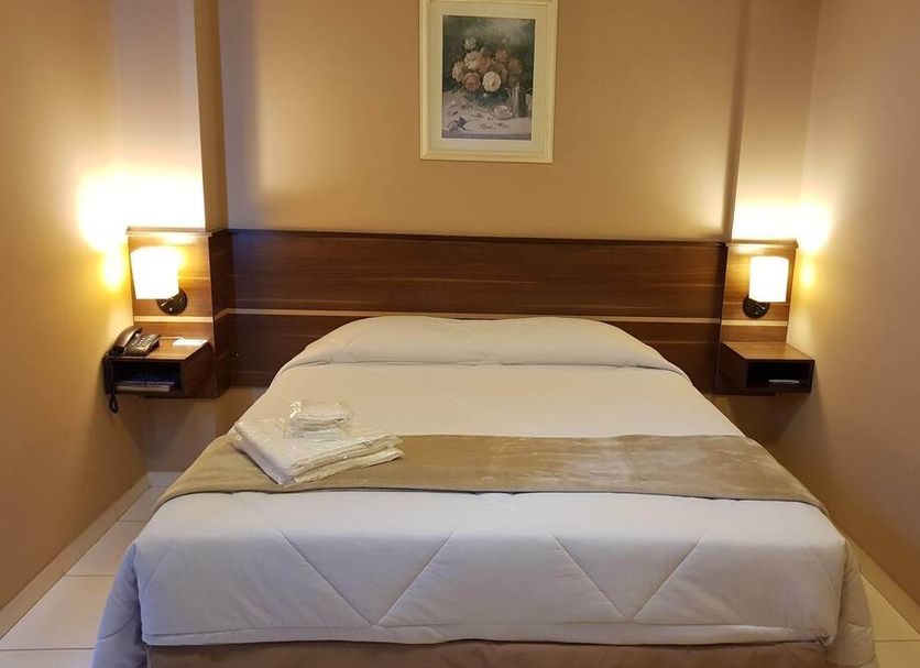 Astro Hotel in São José dos Campos: simple guest room with double bed, bedside lamps, and wall art
