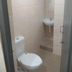Abirami Inn, Kumbakonam: compact tiled bathroom with toilet, wall-mounted sink, and shower area