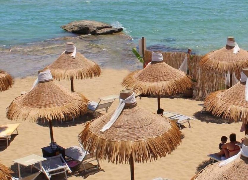 Hotel Noto Marina Vista Mare beach with thatched umbrellas and loungers on sandy shore in Noto