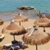 Hotel Noto Marina Vista Mare beach with thatched umbrellas and loungers on sandy shore in Noto