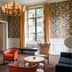 Chateau Cordeillan-Bages Pauillac elegant lounge with floral wallpaper, chandelier, armchairs and window view