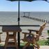 Come Friday Cottages on the Bay in Bacliff with a waterfront patio, table, chairs, and bay pier view