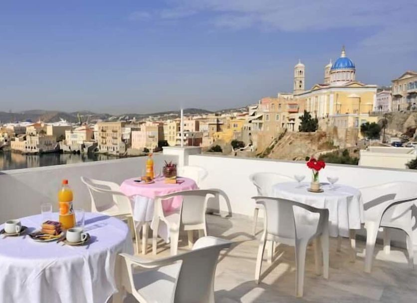 Sea Colours, Ermoupoli: rooftop terrace tables overlooking the harbor and hilltop cityscape
