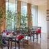 Triose Boutique Hotel Lonavala lounge with tables, chairs and bamboo plants by large windows