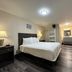Inn at the Sea in Long Beach guest room with king bed, lamps, dresser and vanity