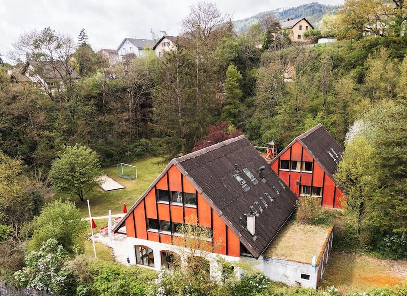 Delémont Youth Hostel in Delémont, hillside setting with orange-roofed chalets and forest views