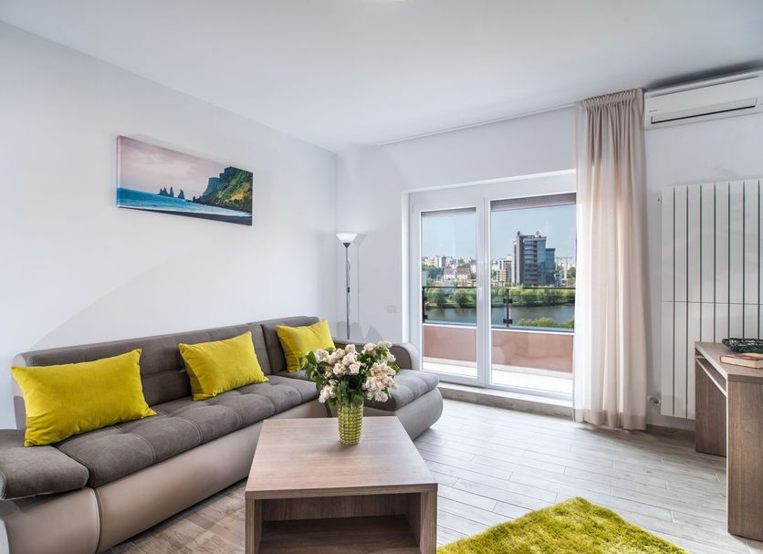Residence iL Lago in Cluj Napoca: living room with sofa, balcony door, and lake view