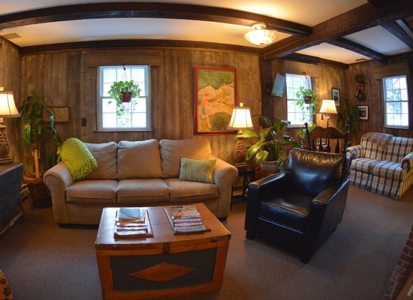 Hyde Away Inn in Waitsfield cozy lobby with sofas, armchairs, coffee table and wood-paneled walls