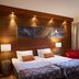 Lapland Hotels Riekonlinna room in Saariselka with twin beds, red armchair and forest-view window