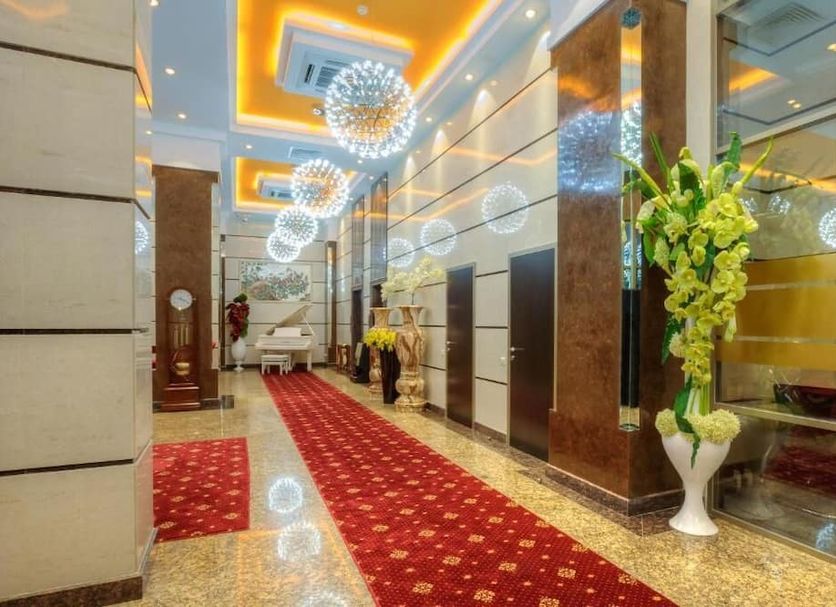 Grand Voyage Hotel in Almaty lobby with red carpet, chandeliers, mirrored walls and floral arrangement