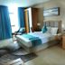 Meshal Hotel & Spa in Manama guest room with king bed, blue accents, desk, chair and round mirror