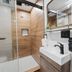 Balboa Park Hotel San Diego bathroom with glass shower, wood-look walls, and vanity sink