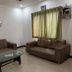 Stayguru Usha Residency in Bhuj lobby with brown sofas, glass coffee table and curtained window