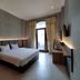 The Grand Palace Hotel Malang guest room with bed, desk, wall TV and balcony door