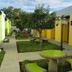 Airport X Managua garden courtyard with lime-green tables, benches, and yellow rooms in Managua